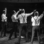 Black and white Rear shot of four men in white shirts with braces