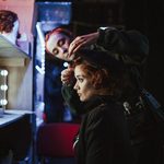 Assistant pins a beret in place backstage