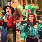 Young white male and young white female in bright elaborate costumes performing a scene from Alice, A Musical Adventure in Wonderland