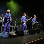 Vanity Fare in navy suits performing on stage, 2 guitarists, 1 keyboardist