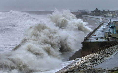 Huge waves batter a sea wall.