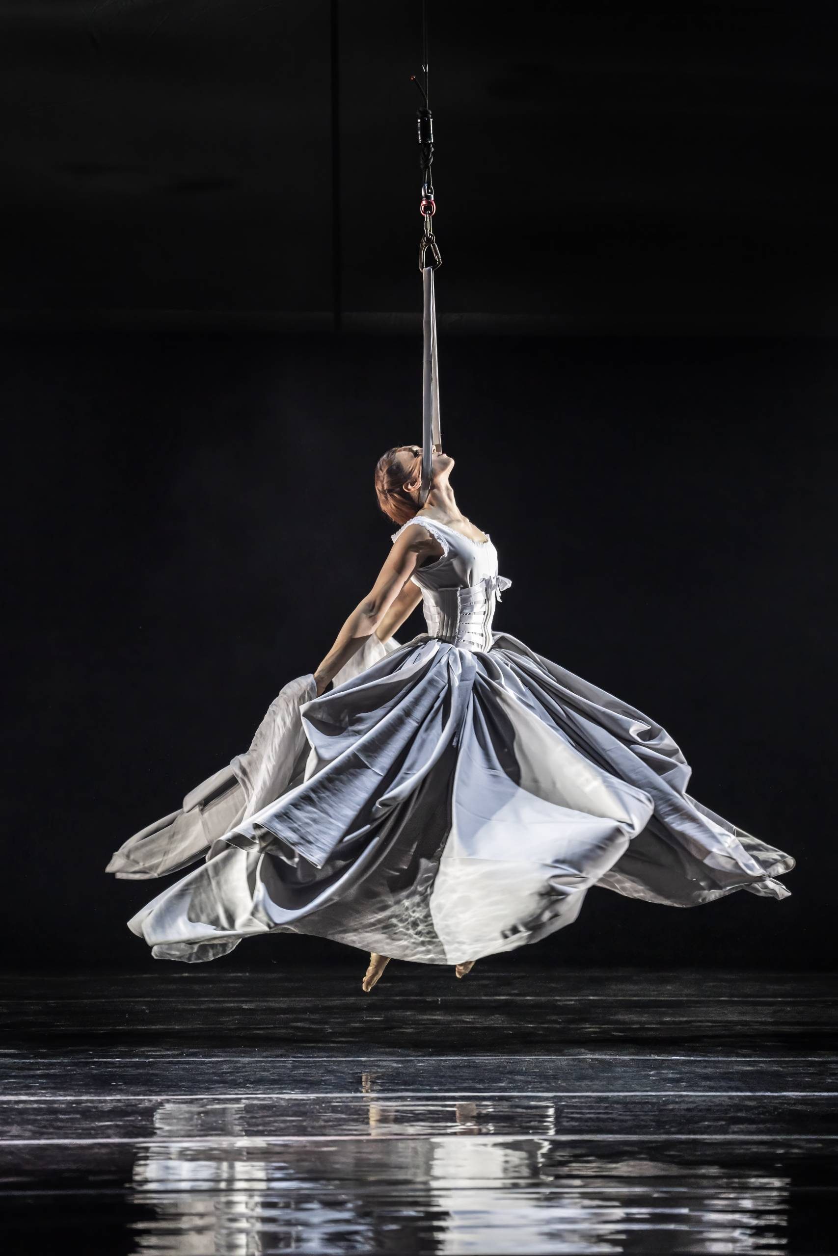 The Polish Mother (Diana Salles) suspended on a rope by her neck, wearing a wide white dress.