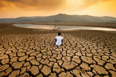 A man sit on dry land in an empty lake