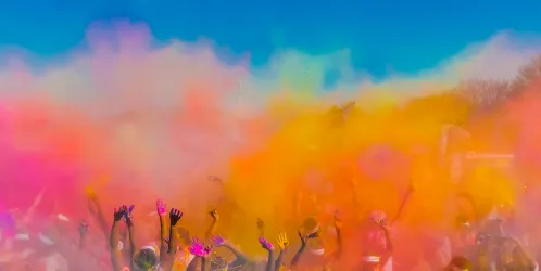 Group of people throwing coloured powder in the air