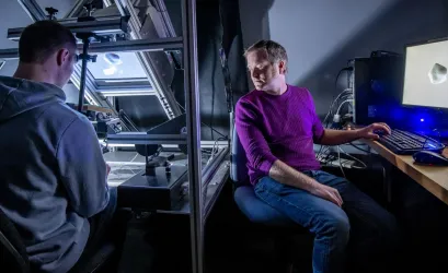 A researcher observes a participant using haptic feedback equipment