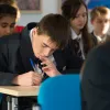 A school pupil writes notes in a classroom setting