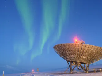 A telescope looking to the sky with borealis lights