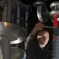 A student using a spanner to adjust a large piece of equipment in the high voltage lab.